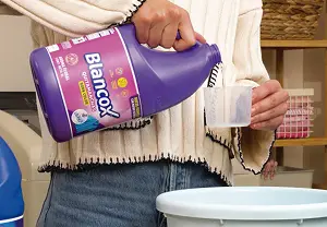 Persona sirviendo en el tarrito de Blancox la cantidad de producto que necesita para lavar