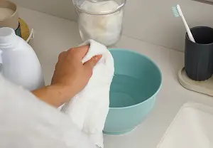 Persona con un paño insertandolo en en producto de blancox con agua